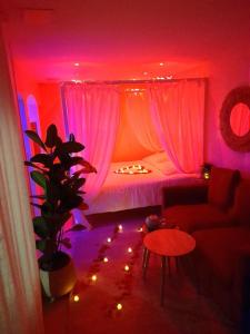 sala de estar con cama con iluminación rosa en L'instant Bornéo Superbe appartement avec jacuzzi, en Liancourt