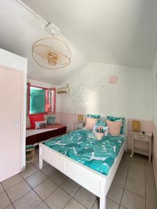 ein Schlafzimmer mit einem weißen Bett und einer grünen Bettdecke in der Unterkunft Hotel De la Plage in Saint-Gilles-les-Bains