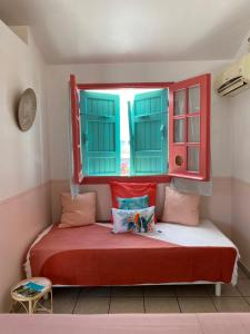 a small bedroom with a bed with a window at Hotel De la Plage in Saint-Gilles-les-Bains
