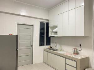 a kitchen with white cabinets and a sink at 休闲民宿 Leisure Homestay @The Venus Sitiawan in Kampong Lumut Kiri