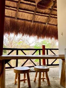 a table with two stools and a thatched roof at Kamajorú Ecohabitat in Tubará
