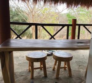 a wooden bench with two stools in front of a window at Kamajorú Ecohabitat in Tubará