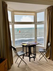 a table and chairs in front of a window with the ocean at Stunning Aberystwyth South Beach Apartment in Aberystwyth