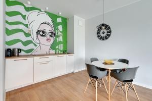 a kitchen with a table and chairs and a painting of a woman at Modern Old Town - Apartament w centrum Gdańska by Grand Apartments in Gdańsk