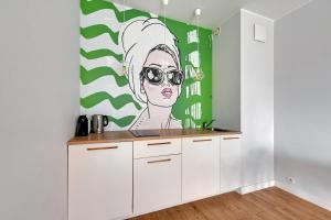 a kitchen with a mural of a woman with sunglasses at Modern Old Town - Apartament w centrum Gdańska by Grand Apartments in Gdańsk