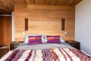 1 dormitorio con 1 cama grande y 2 almohadas moradas en Lujosa Casa Altamira - Villarrica, en Villarrica