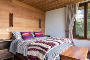 1 dormitorio con 1 cama con pared de madera en Lujosa Casa Altamira - Villarrica, en Villarrica