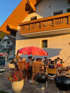 eine Gruppe von Menschen, die an einem Tisch unter einem roten Schirm sitzen in der Unterkunft Ferienwohnung Ramsbacher in Velden am Wörthersee