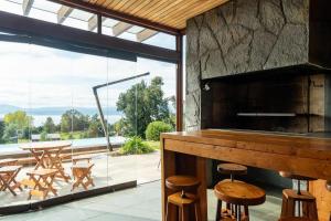 a kitchen with a counter and chairs and a large window at Lujosa Casa Altamira vista al lago e Isla Aillaquillen in Villarrica