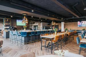 een restaurant met tafels en stoelen en een bar bij Hotel Sportsbar & Brasserie Dorhout Mees in Biddinghuizen