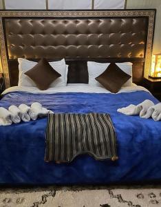 a large bed with a blue blanket and pillows at Luxury Desert Camp in Merzouga