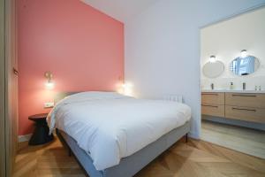 sypialnia z białym łóżkiem i czerwoną ścianą w obiekcie Parisuites Central Grands boulevards Design Folies Bergères w Paryżu +8 zdjęć