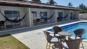 a pool with chairs and a table next to a house at Joias do Nordeste - Chalés para Temporada in Touros