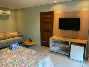 ein Wohnzimmer mit einem Bett und einem Flachbildfernseher in der Unterkunft Villas BobZ in Barrinha