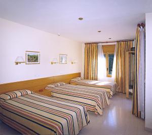 three beds are lined up in a room at Hostal Mallorquines in Riudarenes