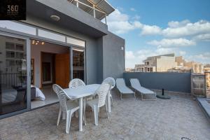 eine Terrasse mit einem Tisch und Stühlen auf dem Balkon in der Unterkunft Comfortable Penthouse, served with LIFT, WIFI & AC by 360 Estates in Gżira