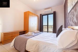 Schlafzimmer mit einem großen weißen Bett und einem Fenster in der Unterkunft Comfortable Penthouse, served with LIFT, WIFI & AC by 360 Estates in Gżira