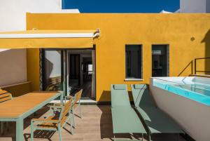 a patio with tables and chairs and a yellow building at Wello Apartments Sevilla in Seville