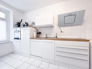 - une cuisine blanche avec des placards blancs et un évier dans l'établissement R&L Apartment Uhlandstrasse, à Leipzig