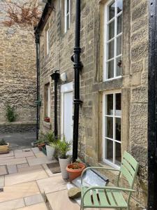 a green chair sitting in front of a building at Beautiful listed 3 bedroom cottage with wood burner in Youlgreave