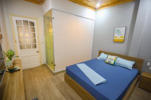 a small bedroom with a blue bed and a door at Radish Cathedral Homestay in Hanoi