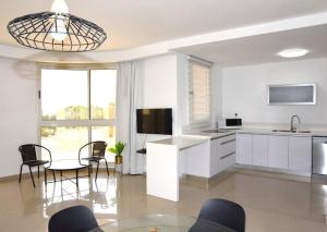 a kitchen and dining room with a table and chairs at Stylish 3BR Golf Residence Eilat in Eilat