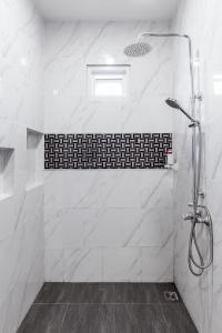 a bathroom with a shower with white marble tiles at Norway Poolvilla in Cha Am
