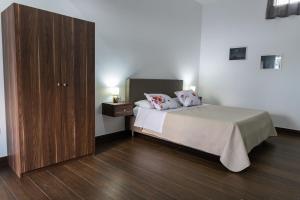 1 dormitorio con 1 cama y armario de madera en Benjoi Camere, en SantʼArpino
