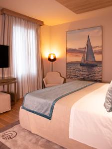 a hotel room with a bed and a sailboat painting at Miramare Suites in Sestri Levante