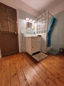łazienka z umywalką, lustrem i drzwiami w obiekcie Le Panoramique w mieście Auvers-sur-Oise