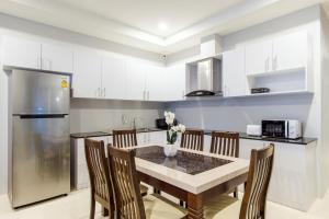 a kitchen with a table and chairs and a refrigerator at Norway Poolvilla in Cha Am