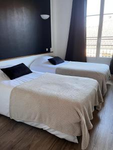 two beds sitting next to each other in a room at Hotel du Pot d'Etain in Châlons-en-Champagne