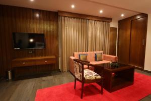 Habitación de hotel con mesa, silla y TV en Hotel Holy Vivasa en Rishīkesh