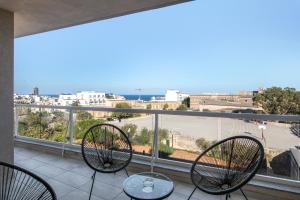 a balcony with three chairs and a view of a city at Spacious, Modern & Cosy 2 Bedroom 2 Bathroom Apartment - St. Julians in St. Julianʼs