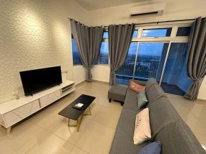 uma sala de estar com um sofá e uma televisão de ecrã plano em AX Residence em Johor Bahru