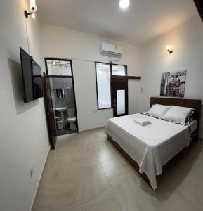1 dormitorio con 1 cama blanca grande y baño en Agradable casa en Buga junto a la basílica, en Buga