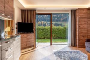 a living room with a tv and a large window at Villa Erina App D2 in Ortisei