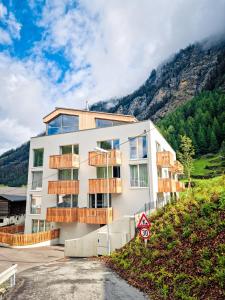 a building on a hill with mountains in the background at All-Suite Resort Zwieselstein - Sölden in Sölden
