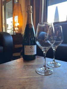 una botella de vino y dos copas de vino en una mesa en Hotel du Pot d'Etain, en Châlons-en-Champagne
