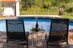 2 sillas y una mesa con una botella y copas de vino en Holiday apartment KALIĆ, en Štokovci