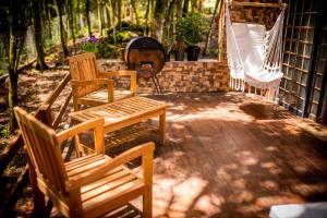 2 sillas y una hamaca en el patio en Chale em Curitiba - Chales Portugal, en Campo Magro