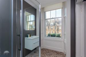 een badkamer met een wastafel, een spiegel en een raam bij No. 53 Frederick Street in Edinburgh