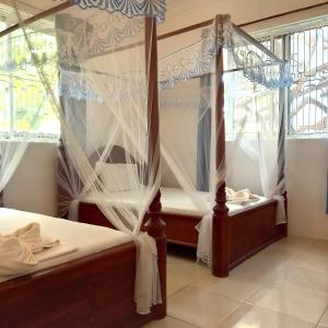 a bedroom with a canopy bed and windows at Atlas Hotel Paje in Paje