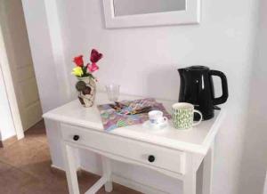 a white table with a coffee pot and flowers on it at Alojamientos Vistas Edén 67 in Caleta De Fuste