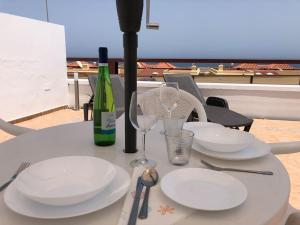 a table with plates and glasses and a bottle of wine at Alojamientos Vistas Edén 67 in Caleta De Fuste