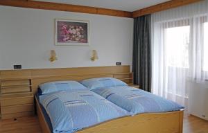 a bedroom with a bed with blue sheets and a window at Haus Klammtal in Schwendau