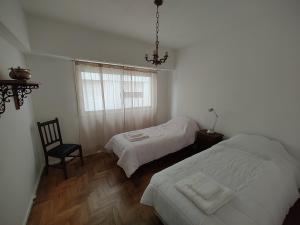 a bedroom with two beds and a chair and a window at Amplio 3 Ambientes Zona Centro in Mar del Plata