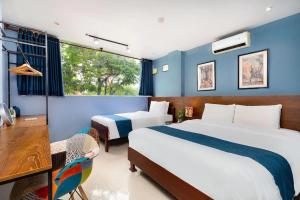 een slaapkamer met 2 bedden, een bureau en een raam bij Hoàng Phi Hotel in Ho Chi Minh-stad