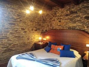 a bed in a room with a stone wall at La Posada de Oscos II in Santa Eulalia de Oscos