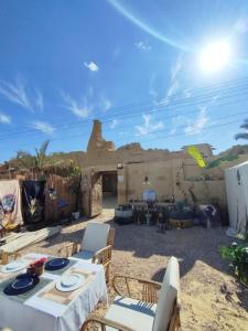 a patio with a table and chairs in the sand at Muhra Camp Siwa in Siwa